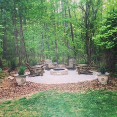 a fire pit surrounded by wooden chairs in the woods