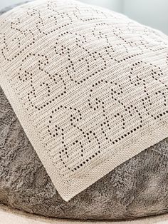 a white knitted pillow sitting on top of a gray and black cushion with holes in it