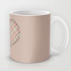 a pink coffee mug with a plaid heart on the front and side, sitting against a white background