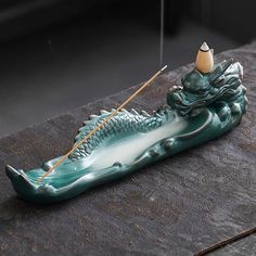 a green dragon boat with a needle in it's mouth sitting on a table