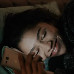 a woman laying in bed with her eyes closed and holding a cell phone to her ear