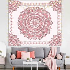 a pink and white wall hanging above a gray couch