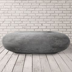 a large gray object sitting on top of a wooden floor next to a brick wall