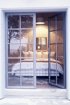 an open bedroom door leading to a bed in the room with white sheets and pillows