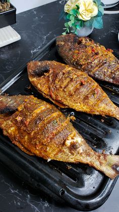 two fish are sitting on a grill pan