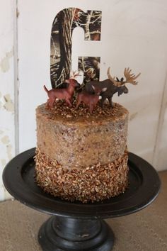 a cake decorated with deer and antlers on top of a black plate in front of a white wall