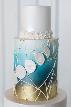 a white and blue cake with gold accents