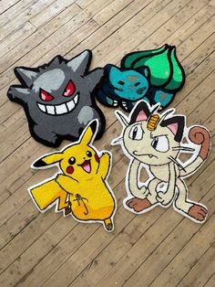 four pokemon stickers sitting on top of a wooden floor