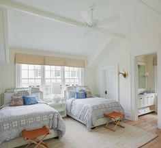 two beds in a room with white walls and wooden floors, along with a window