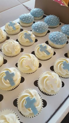 cupcakes decorated with blue and white frosting are on a table in a box