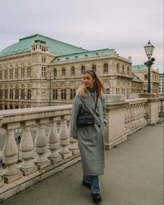 a woman standing on a bridge in front of a large building