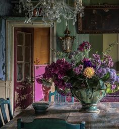 a vase filled with purple flowers sitting on top of a table next to a chandelier