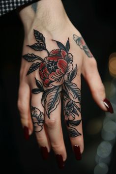 Hand tattoo featuring detailed flowers with red and black ink. Finger Banger Tattoos, Hand Tattoos With Words, Card Size Tattoos Ideas, Hand Tattoos For Women American Traditional, American Traditional Thumb Tattoo, Best Finger Tattoos For Women, Women Knuckle Tattoo Ideas, Traditional Tattoo On Hand, Smaller Tattoo Ideas For Women