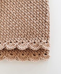 a crocheted blanket is laying on top of a white surface with the edges folded down