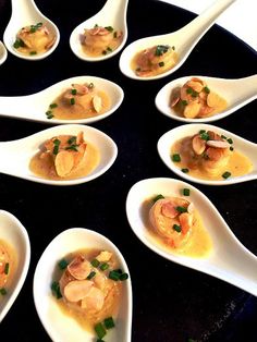 spoons filled with different types of food on top of a black plate and white serving utensils