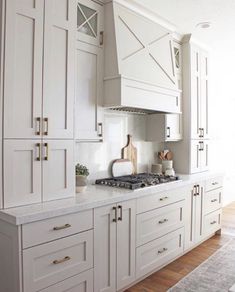 a kitchen with white cabinets and an oven on the counter top in front of it