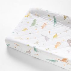 a baby crib mattress with dinosaurs and stars on it's side, in white