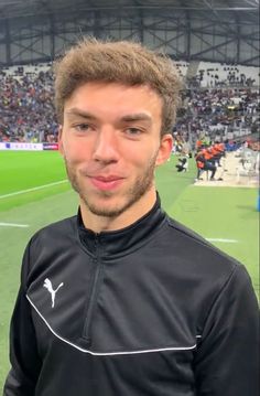 a man standing on top of a soccer field wearing a black jacket with white piping