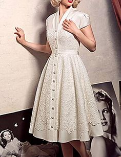 a woman in a white dress is standing next to a wall with pictures on it