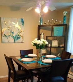 a dining room table is set with plates and flowers