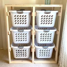 four plastic laundry baskets stacked on top of each other in front of a wooden shelf