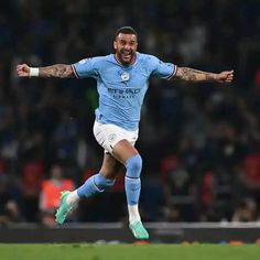 a soccer player with his arms out and one foot in the air as he runs towards the ball