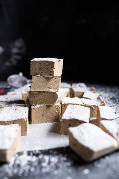 several pieces of brown and white cake sitting on top of a table covered in powdered sugar