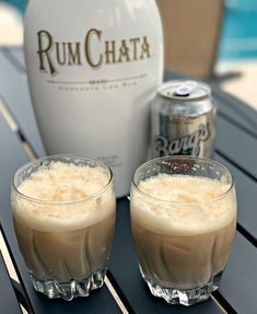 two glasses filled with liquid sitting on top of a table next to a bottle of rumchata