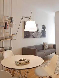 a living room filled with furniture and a white dining table surrounded by chairs in front of a wall mounted book shelf