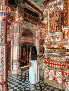 a woman in a white dress is looking at the colorfully painted walls and ceiling