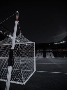 an empty soccer field at night with the goal in front of it and lights on