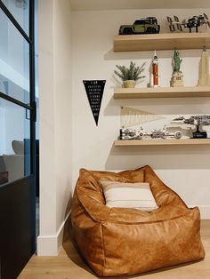 a brown bean bag chair sitting on top of a hard wood floor next to shelves