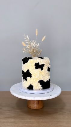 a cake with black and white frosting on a wooden table next to a gray wall