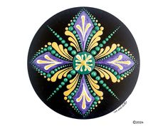 an artistically painted black and yellow flower design on a round surface with green dots