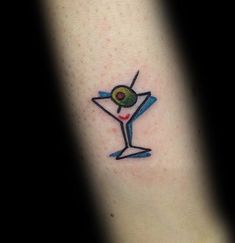 a tattoo with a martini glass and olive on it