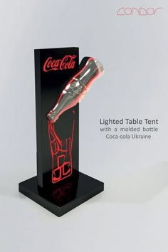 an illuminated table tent with a moulded bottle and coca - cola urn