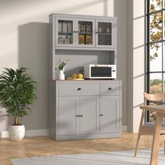 a kitchen area with a microwave, cabinet and potted plant