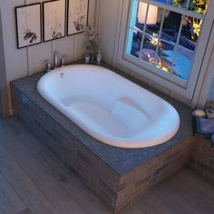 a bathroom with a large jacuzzi tub next to a window and pictures on the wall