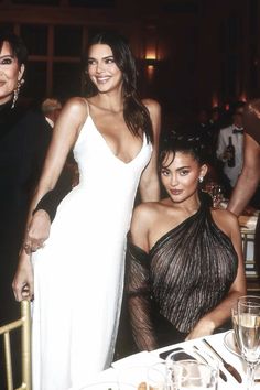 two women sitting next to each other at a table with wine glasses and plates on it