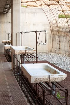 several sinks are lined up against the wall in an industrial area with exposed pipes and scaffolding