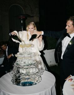 a man and woman standing next to a tall cake on top of a white table