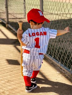 a young boy wearing a baseball uniform and holding a bat