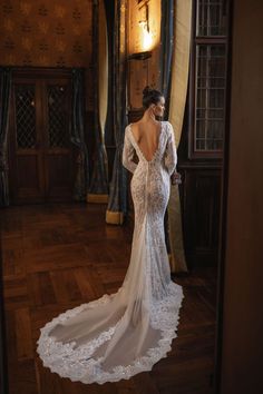 a woman in a wedding dress looking at herself through the door to another room that is decorated with curtains