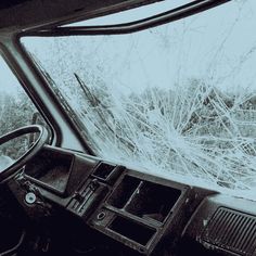 the interior of a car with shattered glass on it's windshield and trees in the background