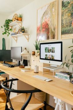 a desk with two computer monitors, keyboard and mouse on it in front of some plants