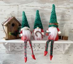 three green and red gnomes sitting on top of a shelf