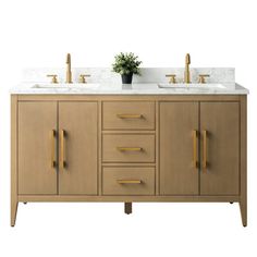 a bathroom vanity with two sinks and gold faucets on the counter top next to a potted plant