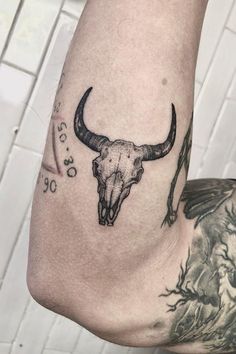 a man's arm with a bull skull tattoo on it