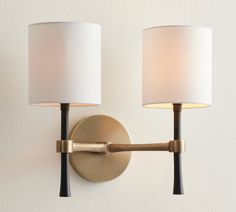 two lamps mounted on the wall next to each other, one is white and the other is gold