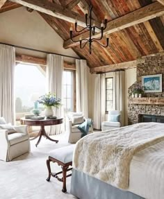 a bedroom with a bed, two chairs and a fireplace in the middle of it